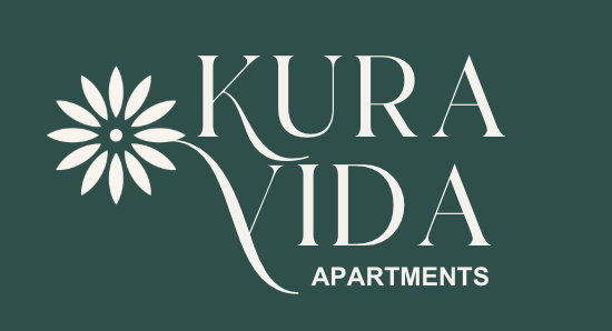 Kura Vida Apartments logo: white text on dark green background, stylized flower to the left.