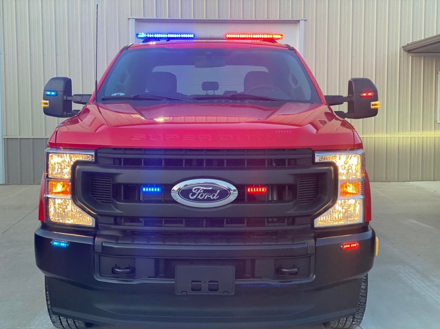 A red ford truck with a blue light on top of it is parked in a parking lot.