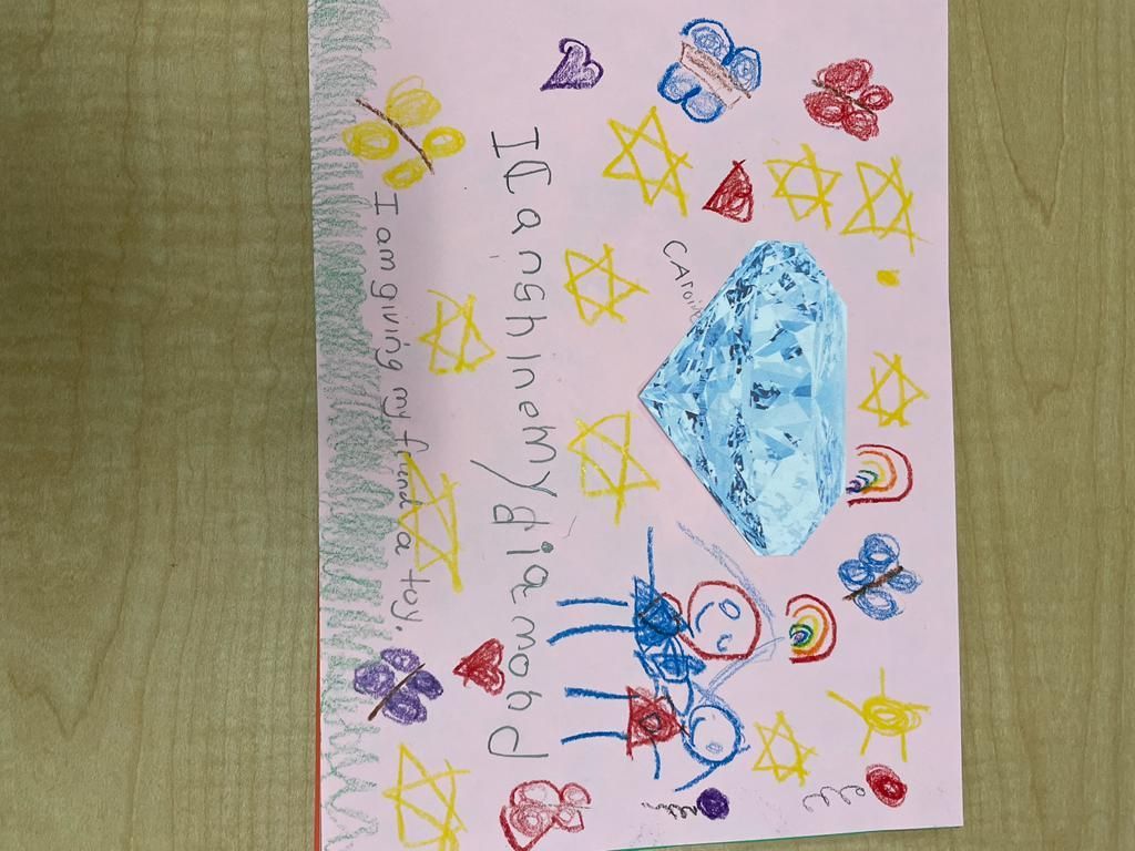 Child’s crayon drawing on paper with stars, butterflies, rainbows, a blue cloud, and “I love my grandma” text.