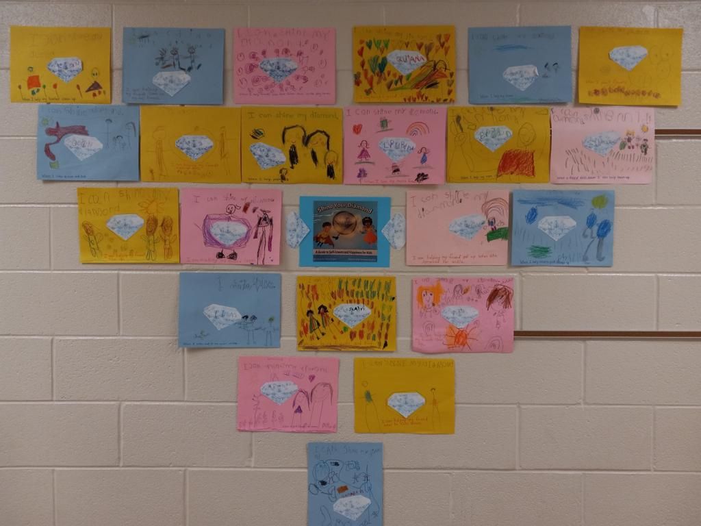 Colorful children's drawings and cards arranged in a heart shape on a tiled wall.