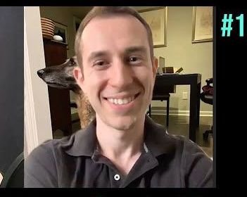 Smiling person indoors in a dark polo shirt, sitting in a room with furniture behind them.