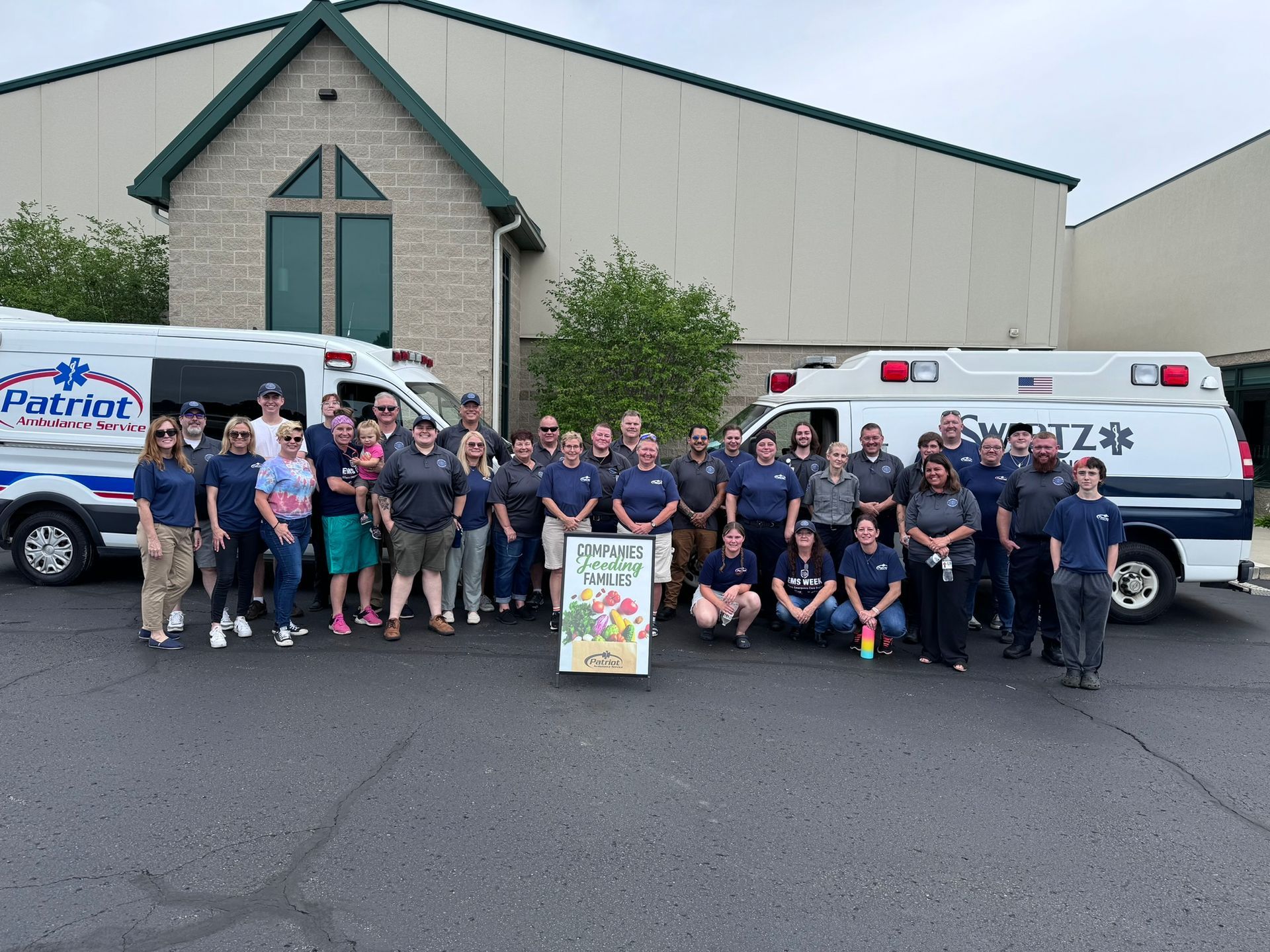 Group of people with ambulances posing in front of a building.