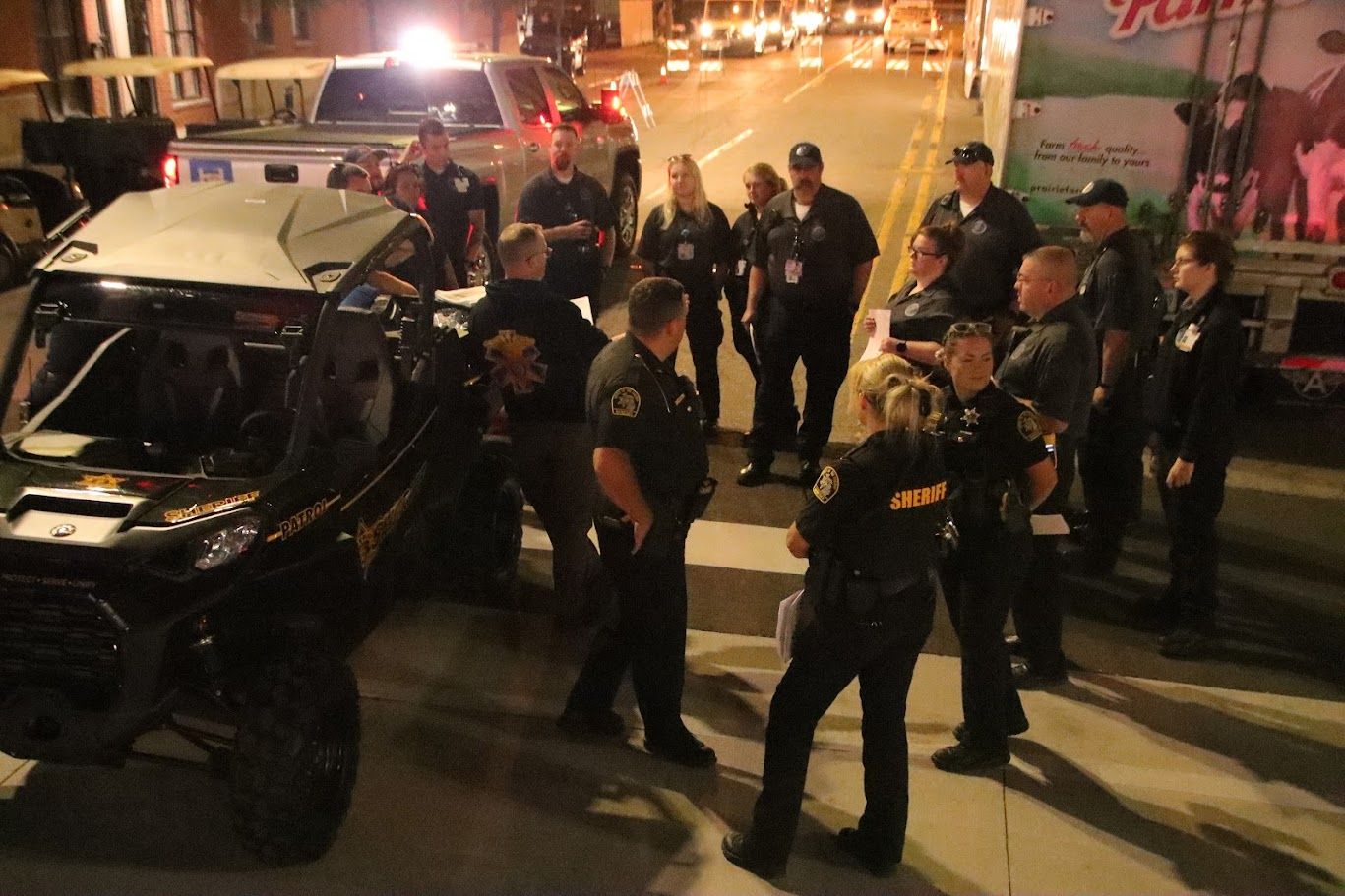 Police officers gather around a damaged utility vehicle at night on a city street.
