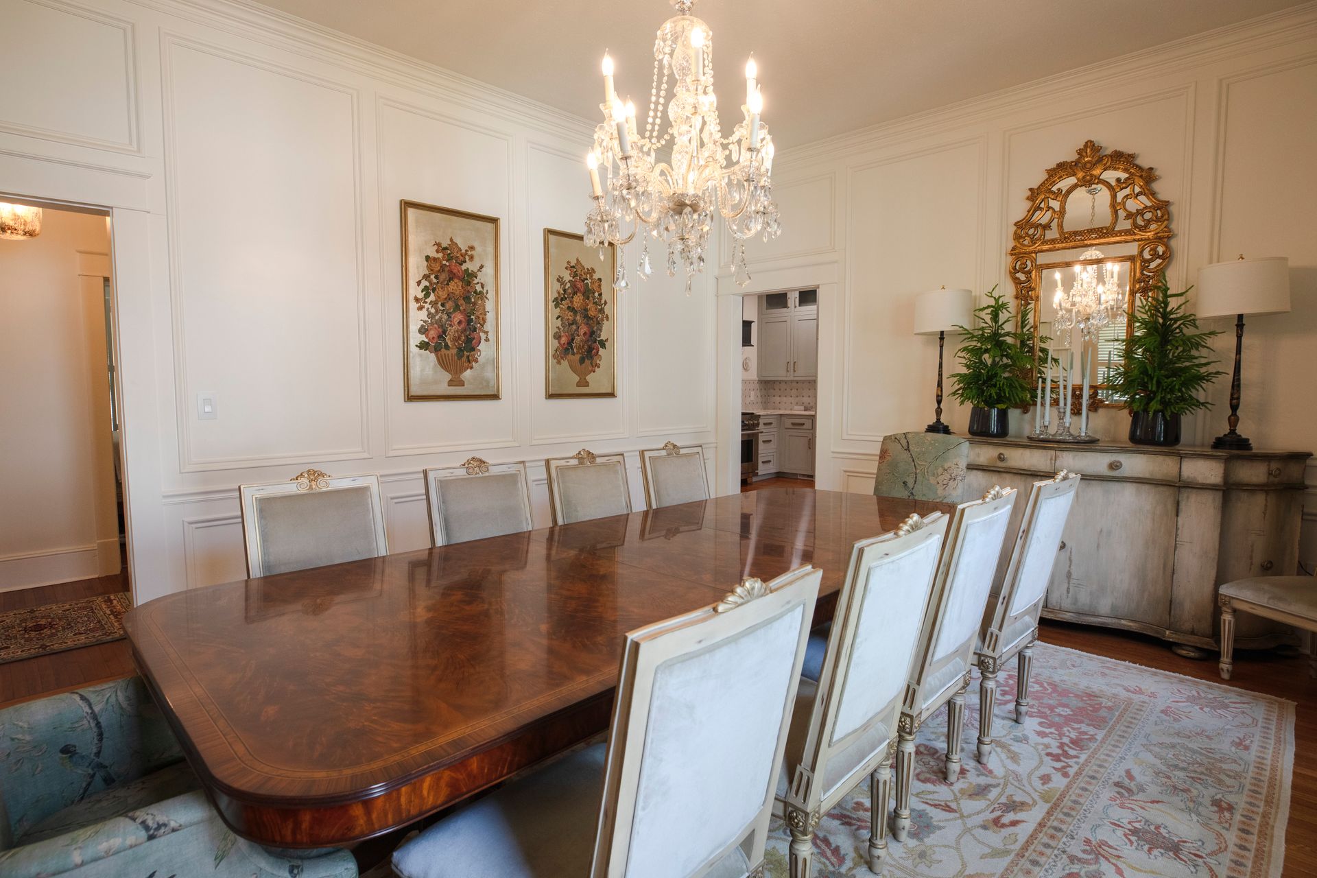 Elegant dining room with long table, chandelier, artwork, and white walls.