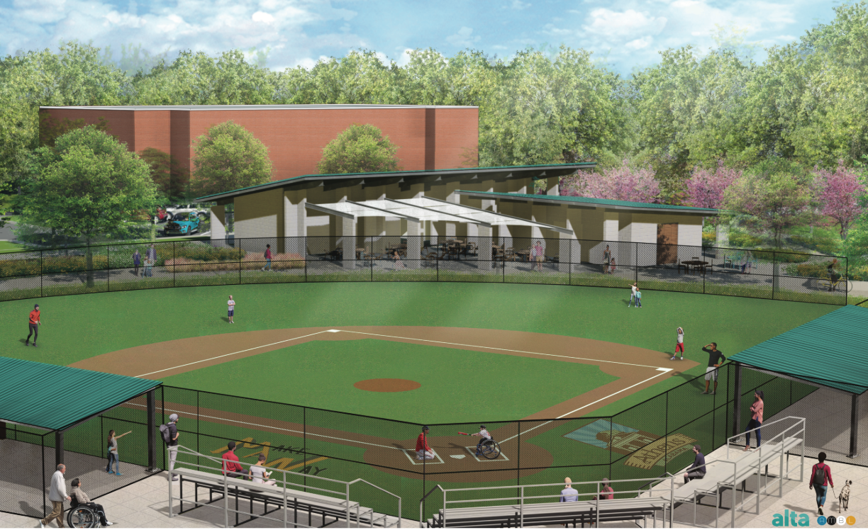 Baseball field with stands, players, and a tree-lined park backdrop under a blue sky