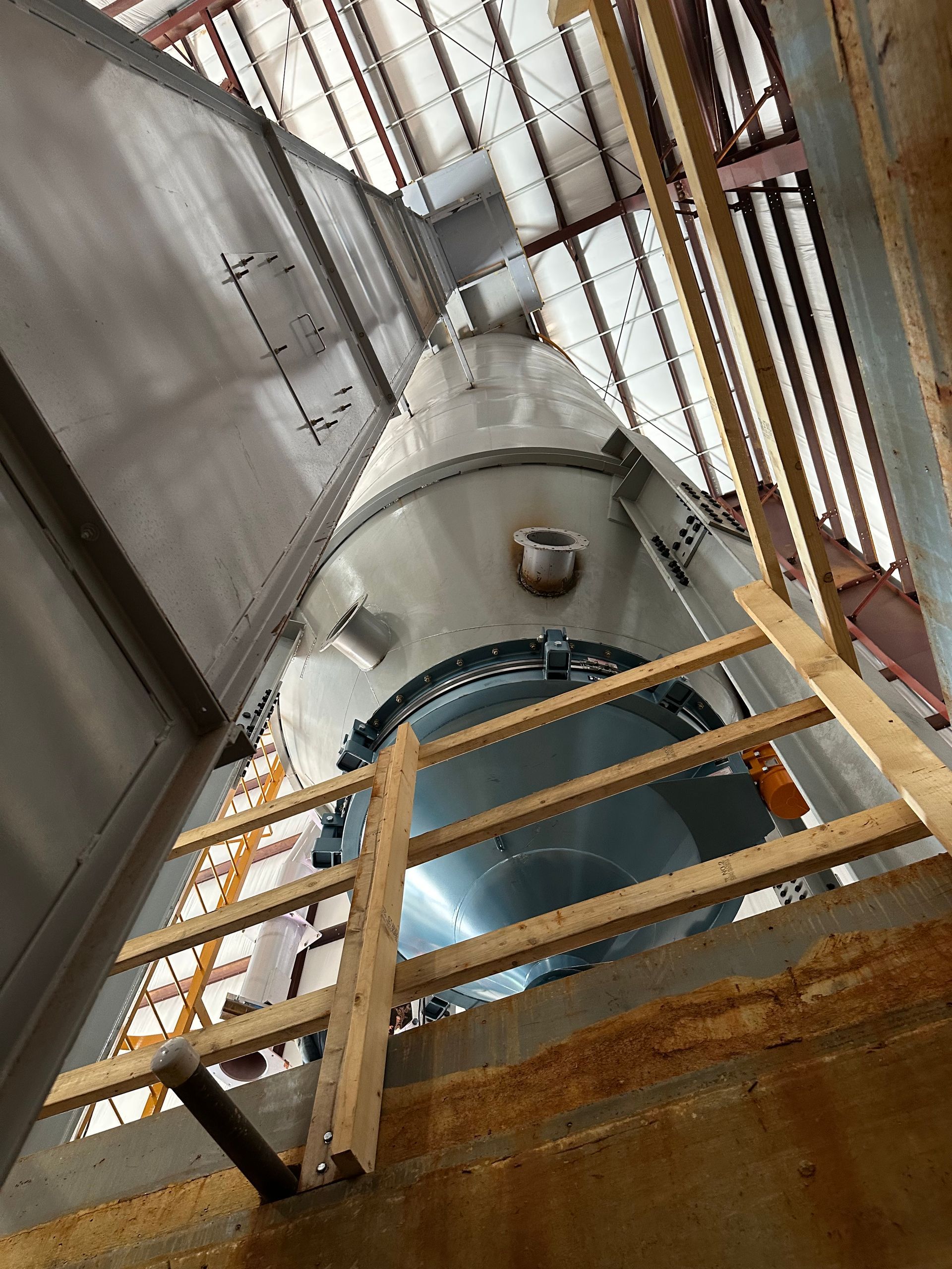 Steel industrial tower viewed from below, with a wooden ladder and a metal roof.
