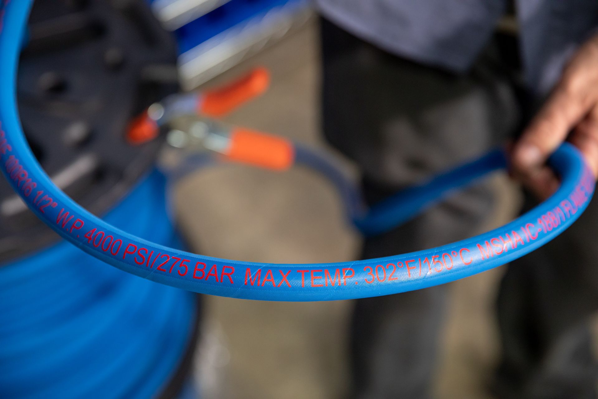 A person is holding a blue industrial hose in their hand.