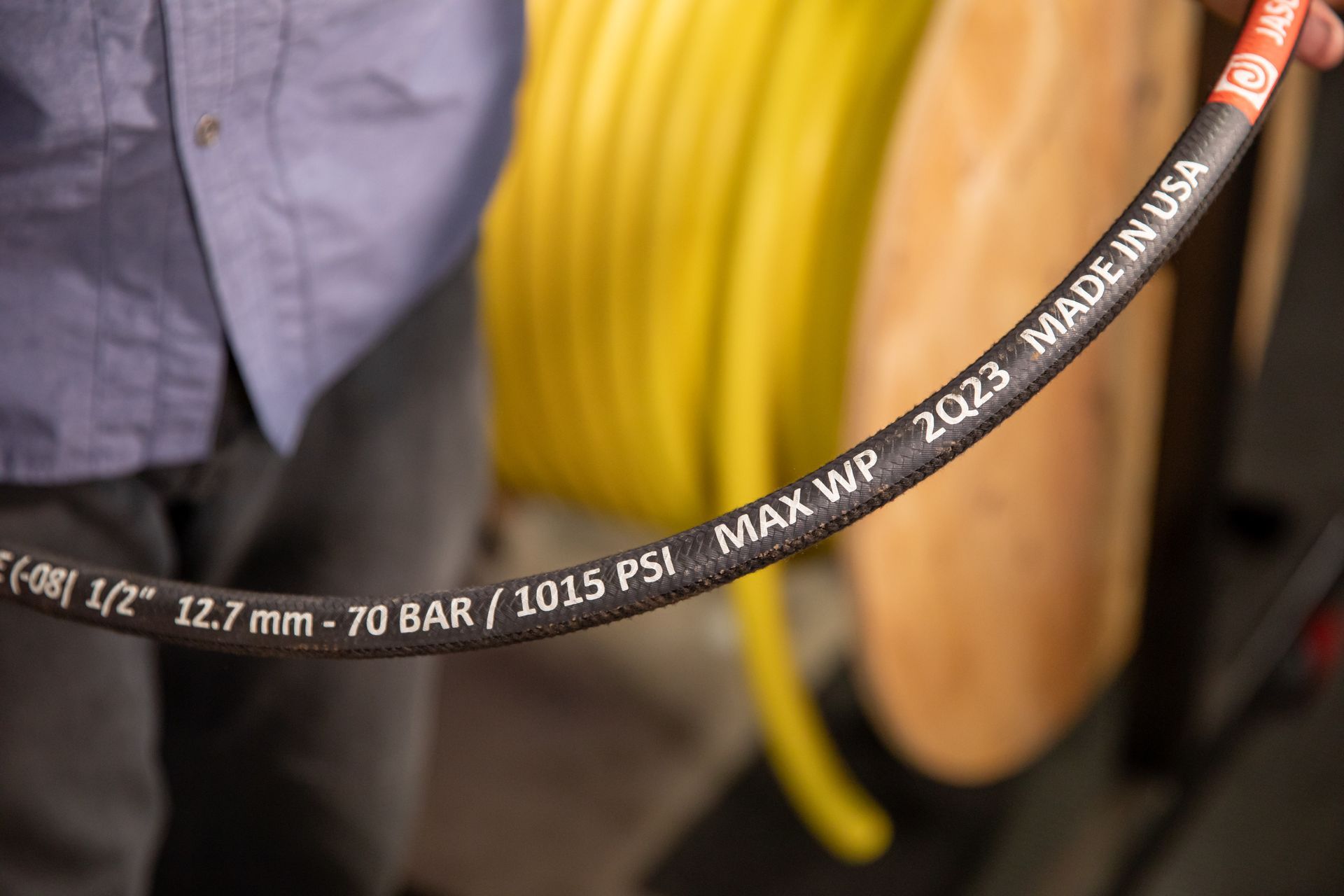 A man is holding an industrial hose that is made in the USA.