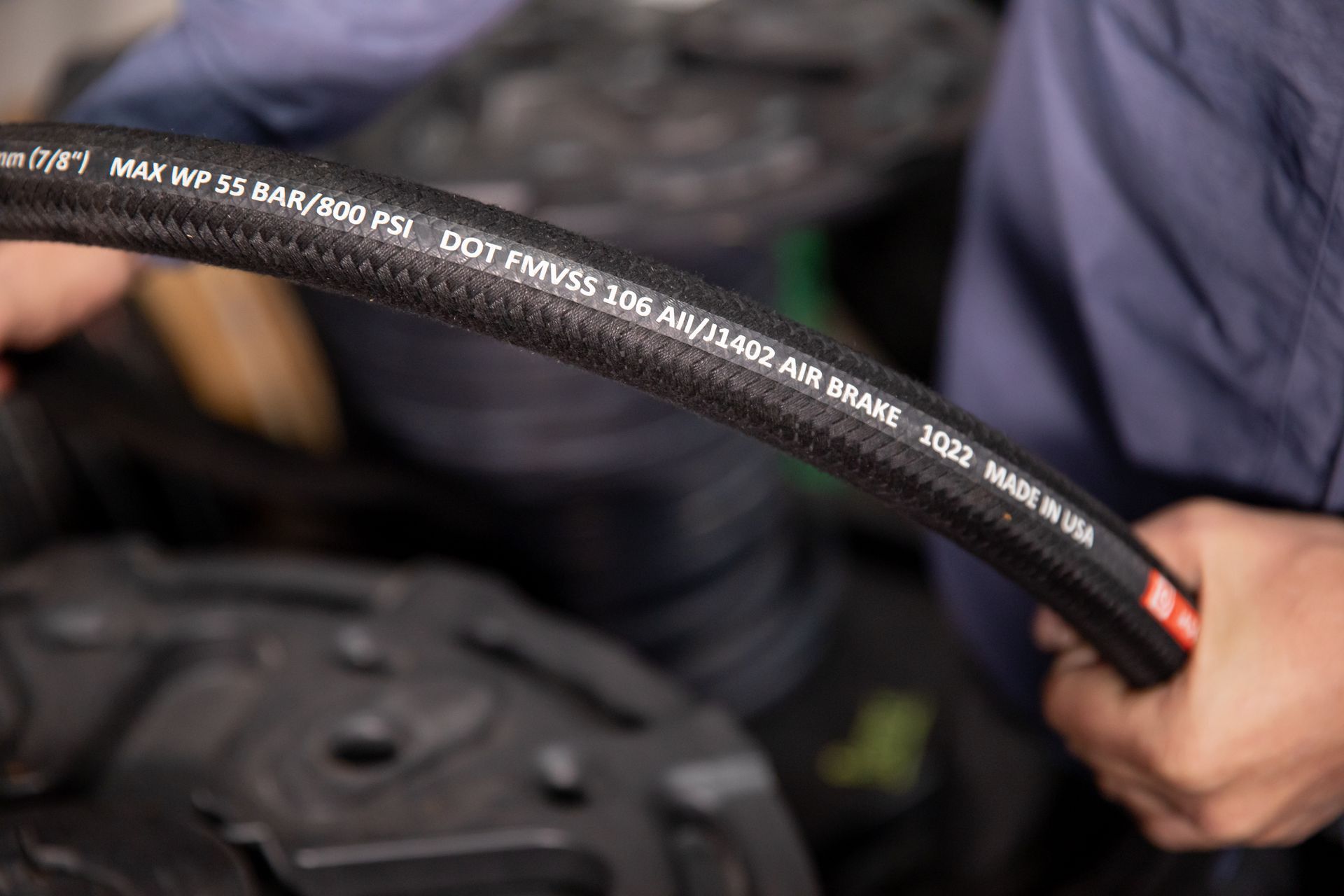 A close up of a person holding a black hydraulic hose