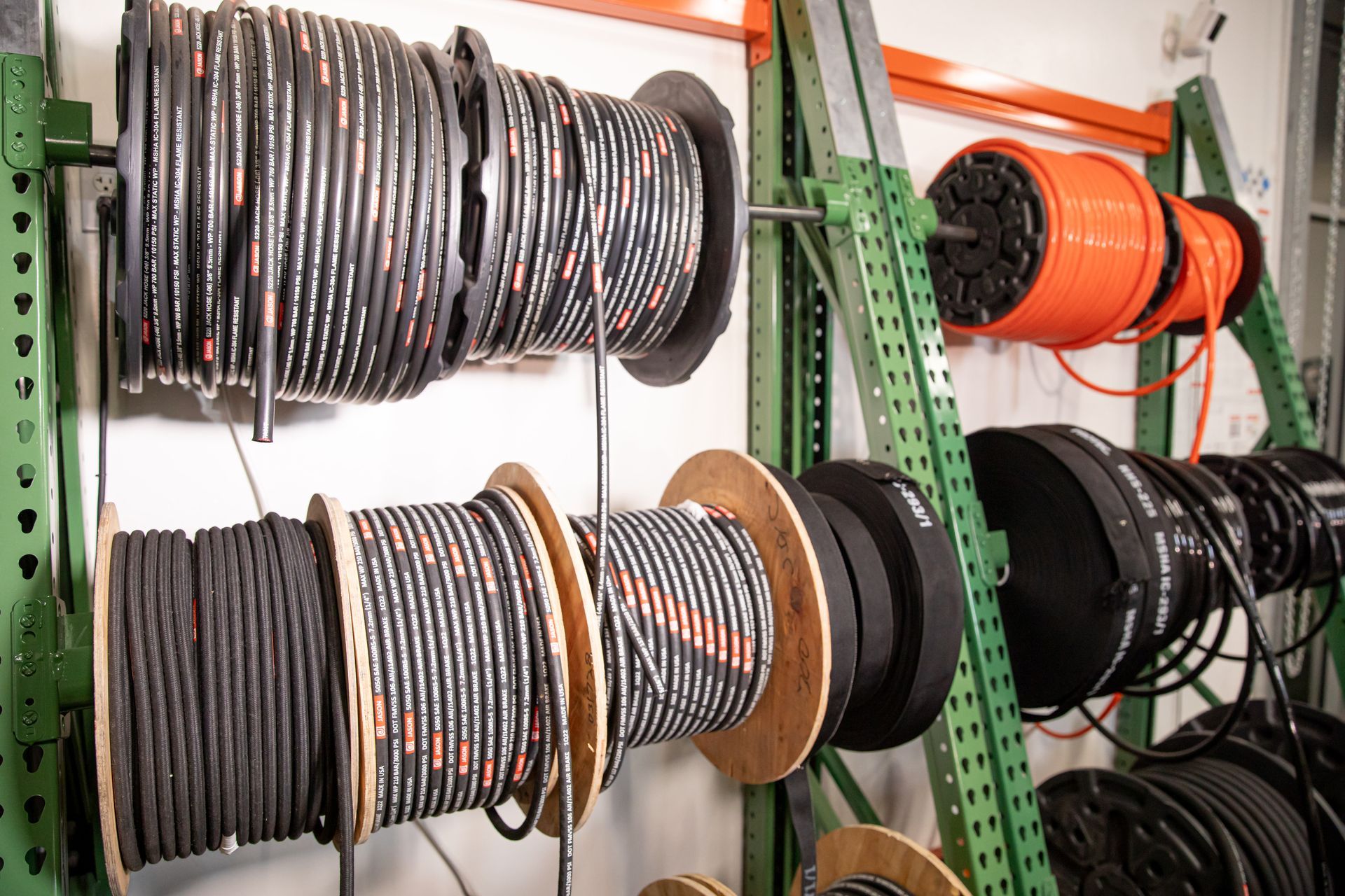A bunch of spools of hydraulic and industrial hoses hanging on a rack