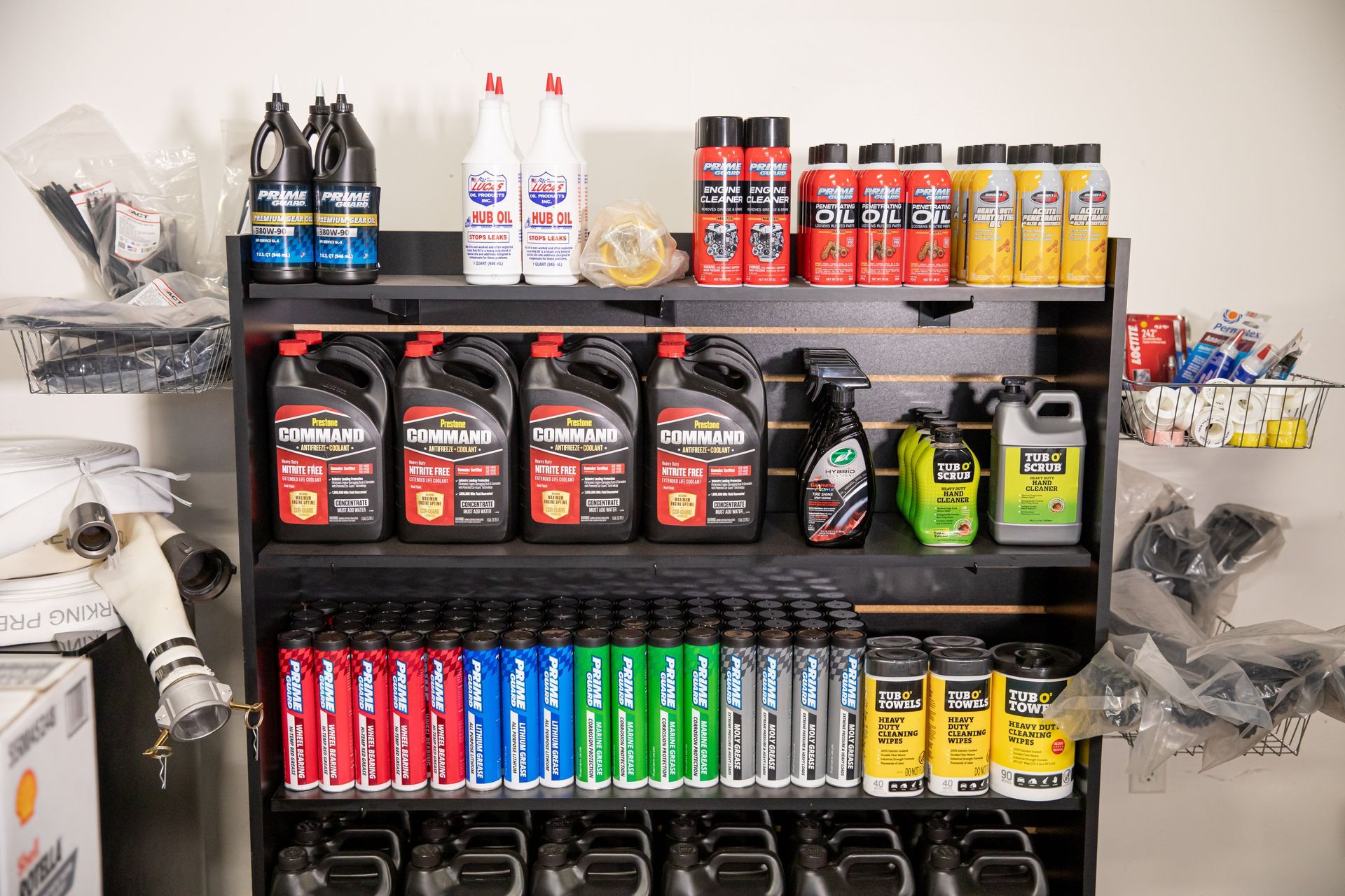 A shelf filled with lots of bottles of products for hydraulic and industrial hoses.