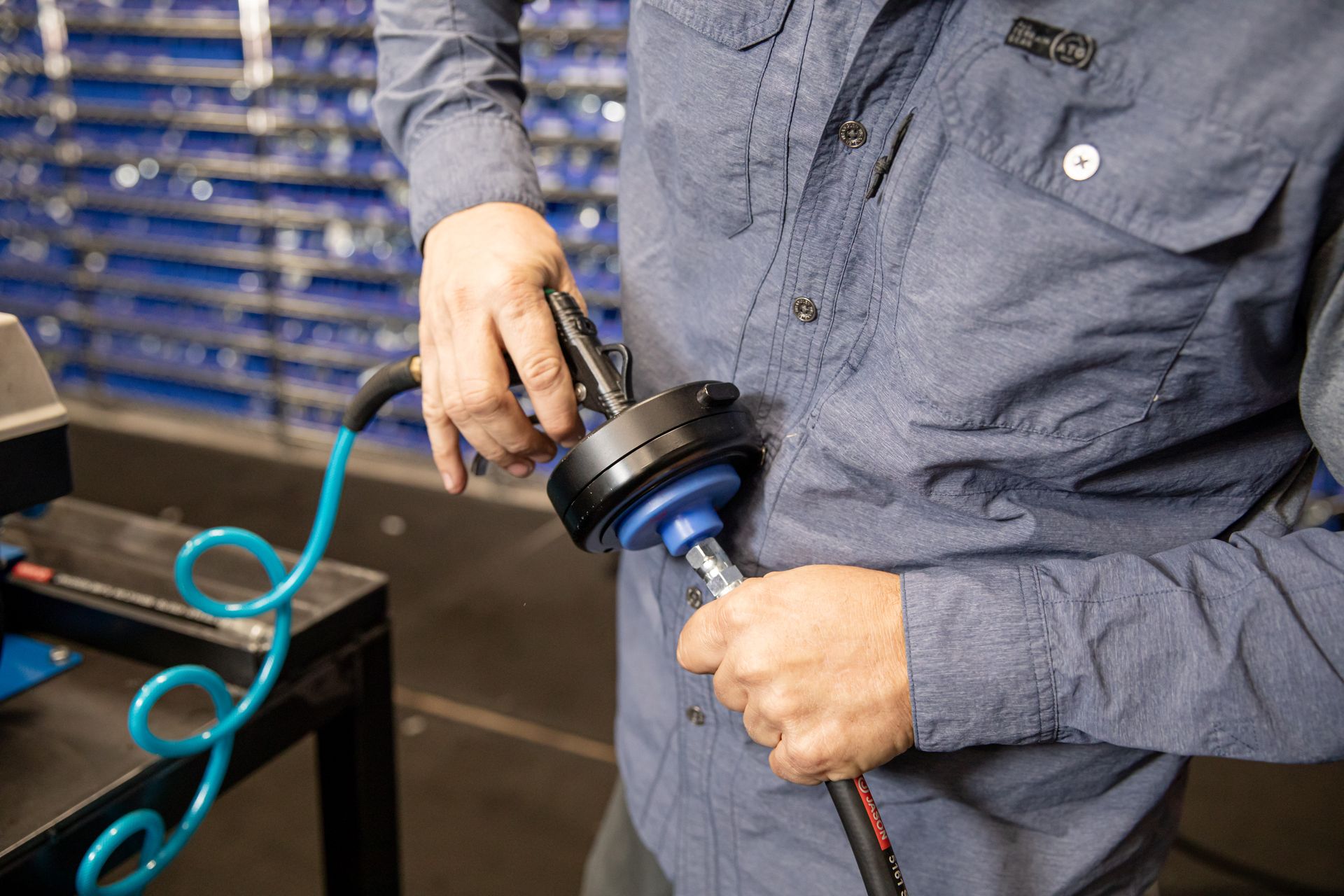 A man in a blue shirt is holding a tool in his hands.