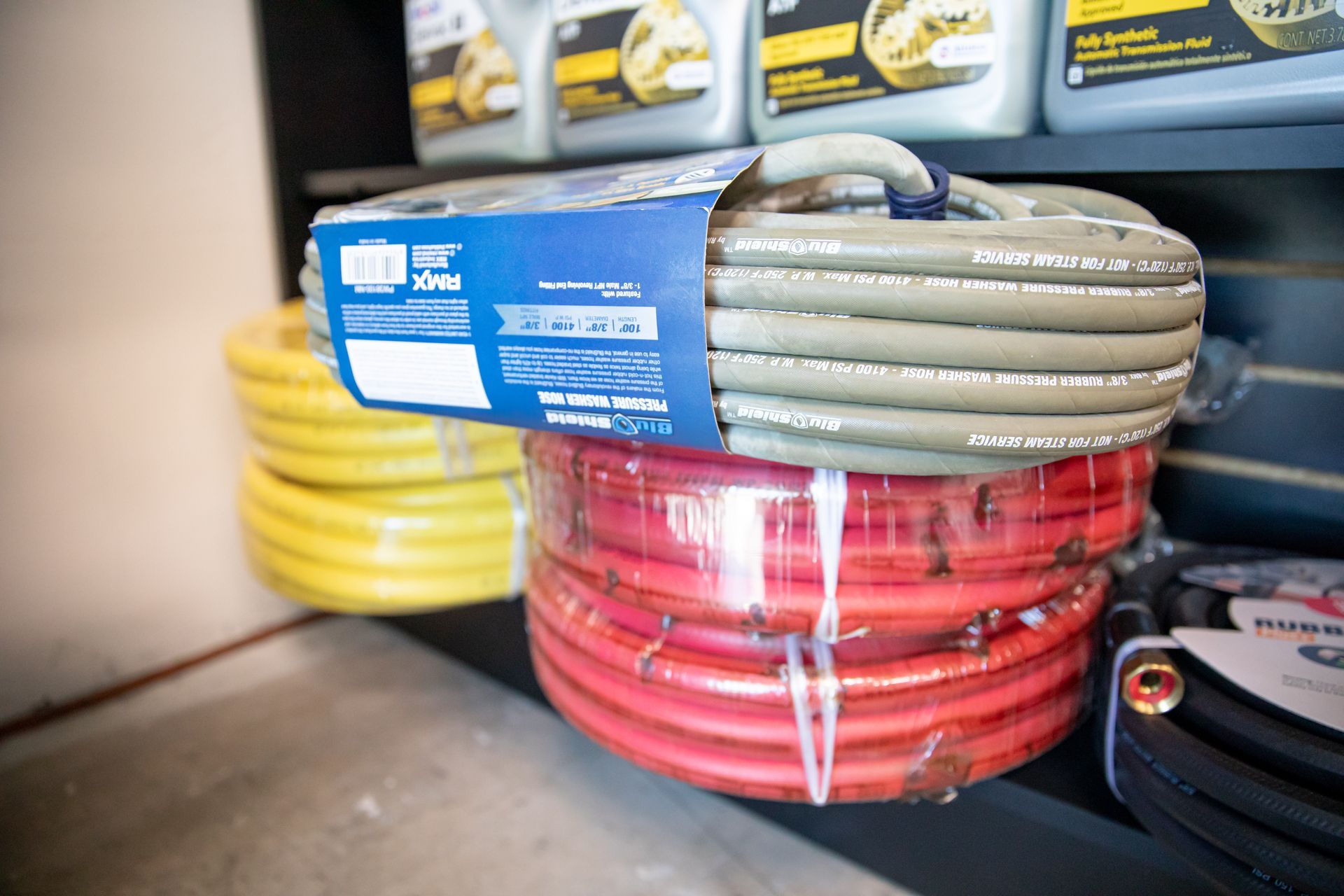 A bunch of hydraulic and industrial hoses are stacked on top of each other on a shelf.