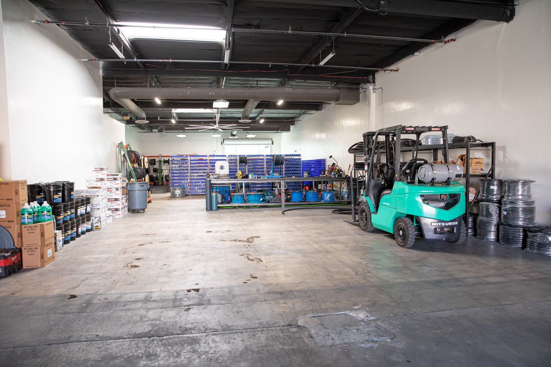 A green forklift is parked in a large workshop.