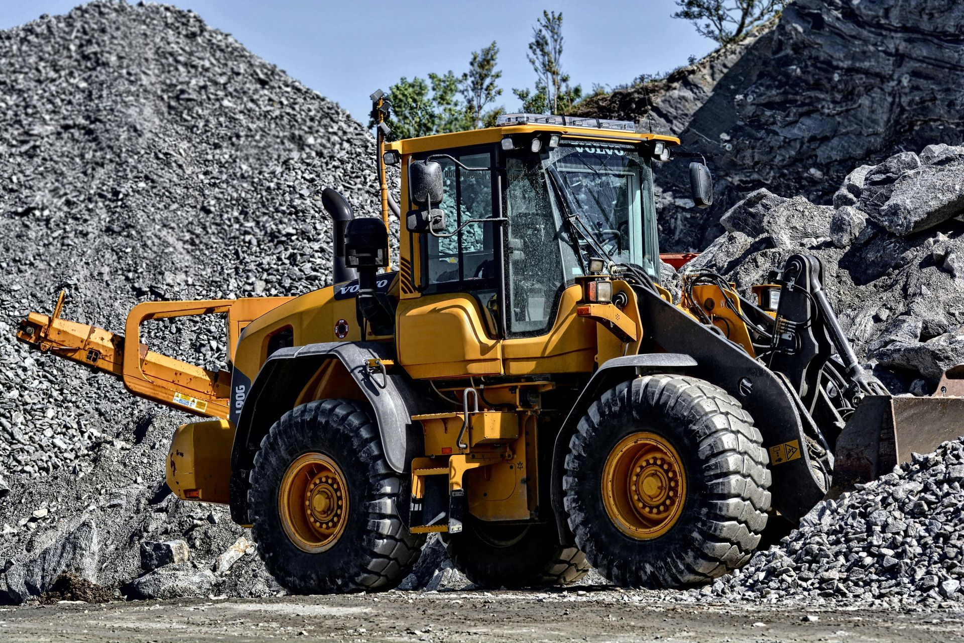 Yellow front-end loader scoops rocks at a quarry.