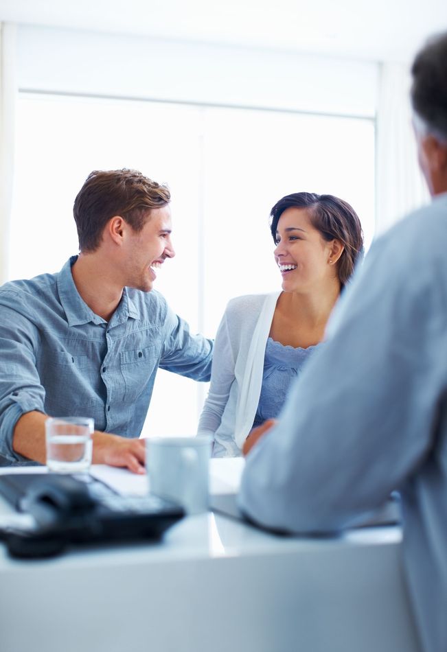 Two coworkers smiling and talking at a bright office meeting table