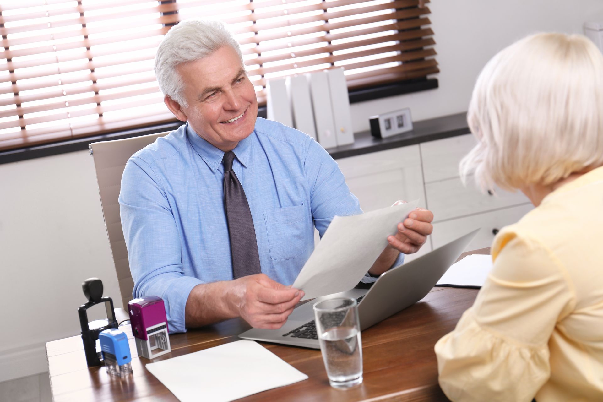 Doctor reviewing papers with a patient across a desk in a bright office.