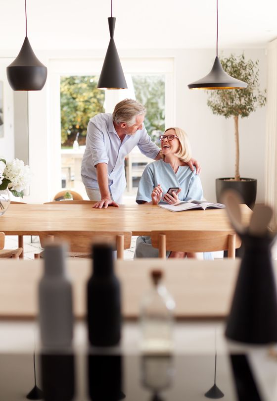 Two people chatting in a bright café beside a wooden table and hanging pendant lights