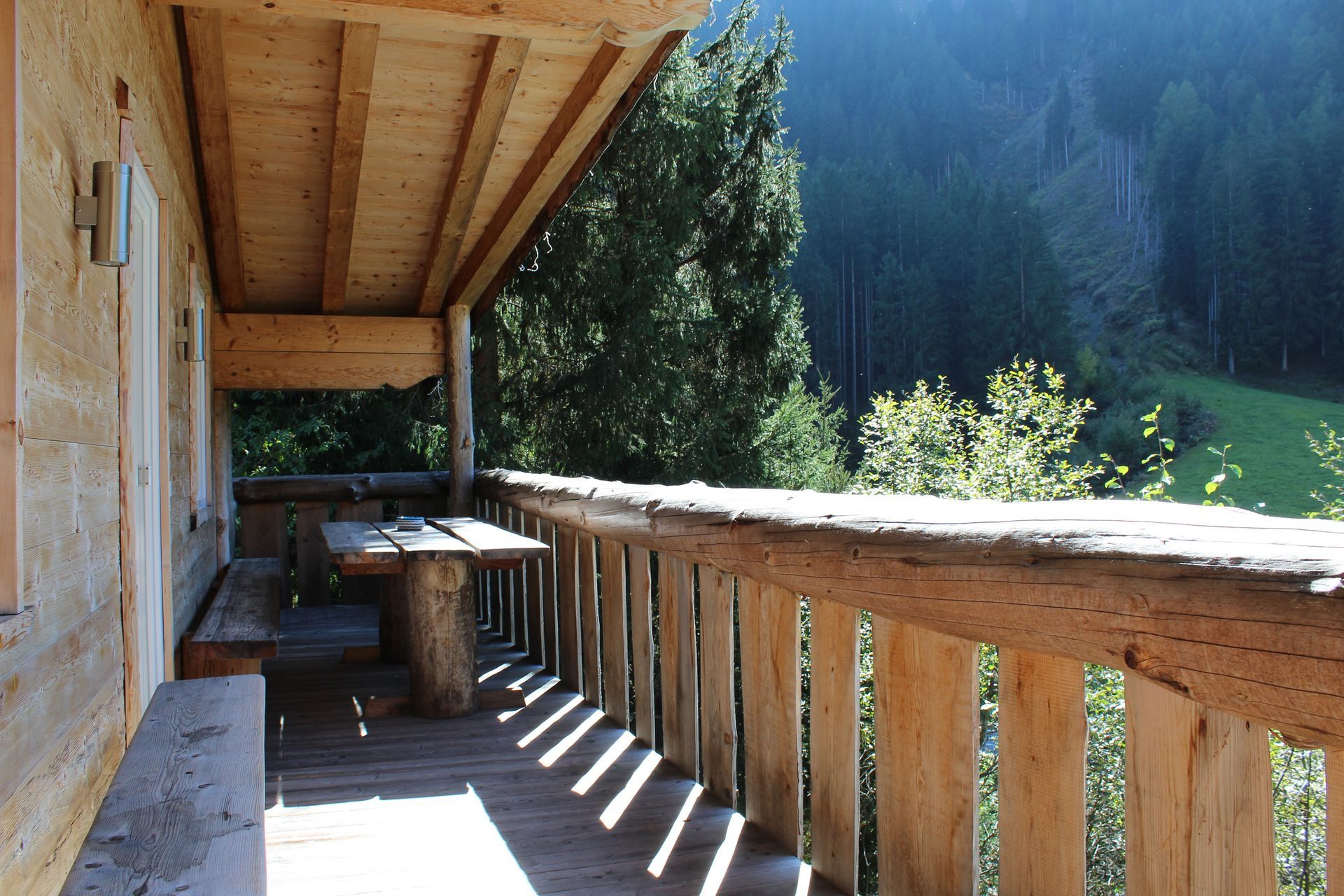 Ein rustikaler Holzbalkon mit Tisch und Bank