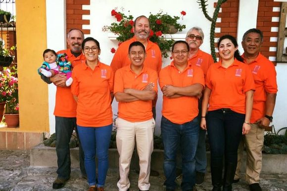 Group of people in orange shirts posing together outdoors in front of a decorated entrance
