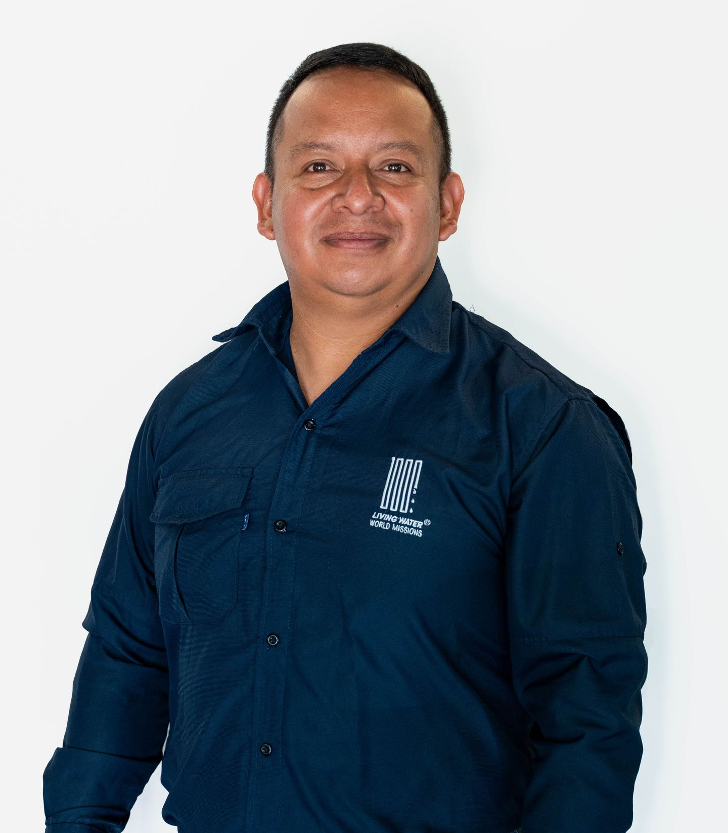 Smiling person in a light beige shirt standing against a white background