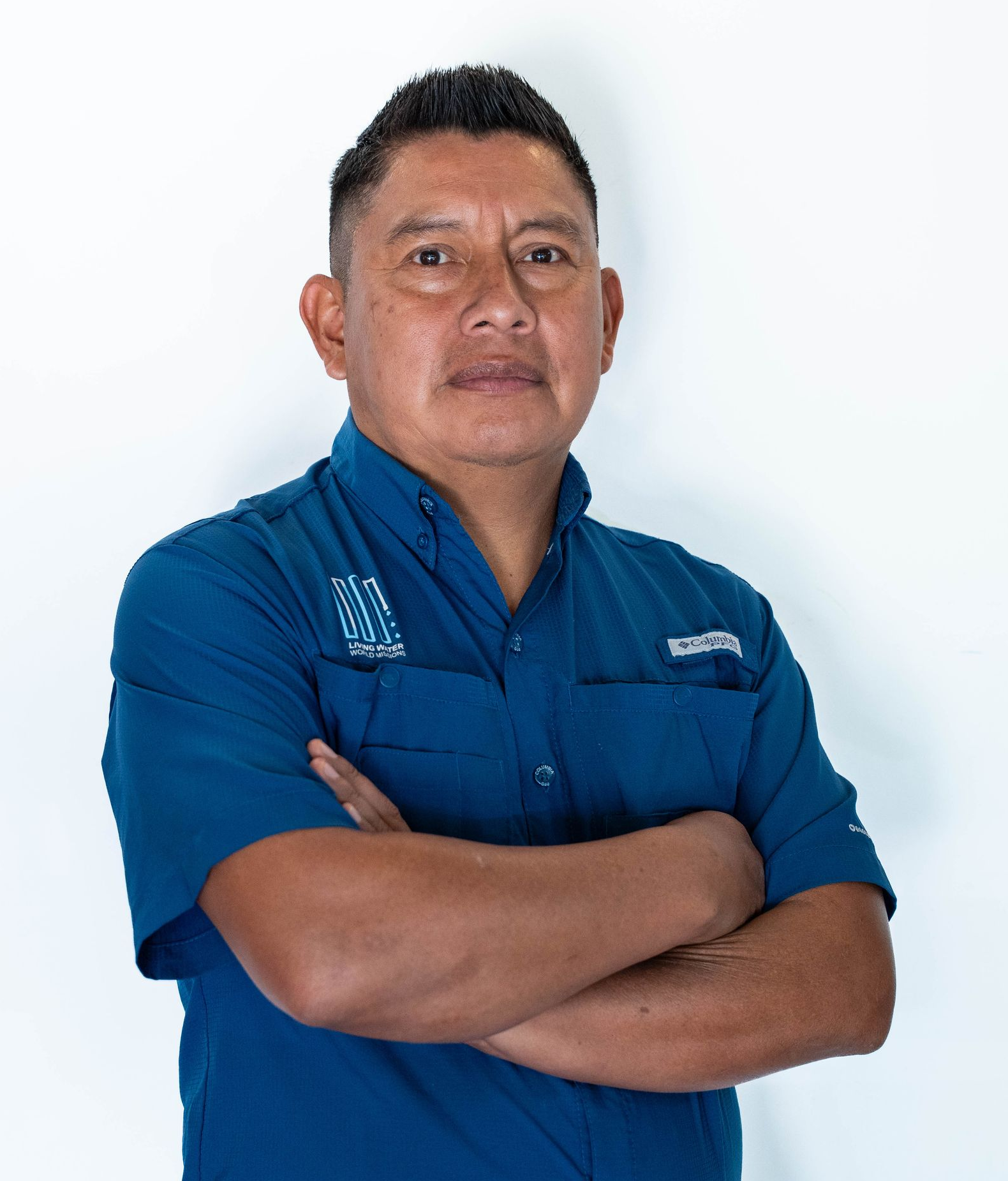 Portrait of a man in a light beige button-up shirt against a white background