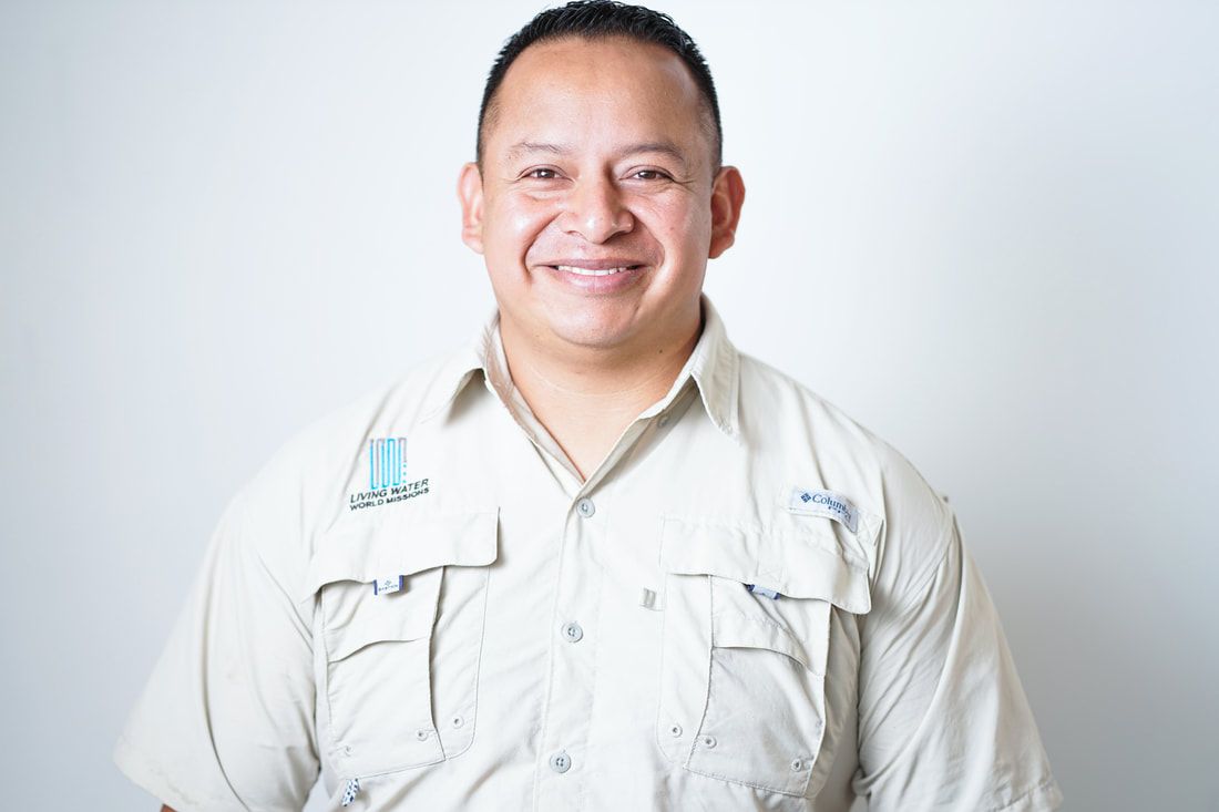 Smiling person in a light beige shirt standing against a white background