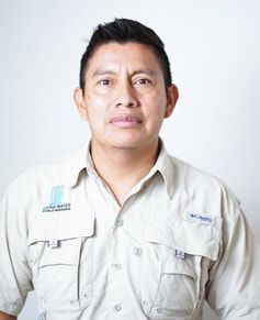 Portrait of a man in a light beige button-up shirt against a white background