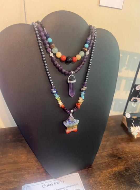 Multi-strand beaded necklaces on a black display bust, including a central pendant and colorful beads