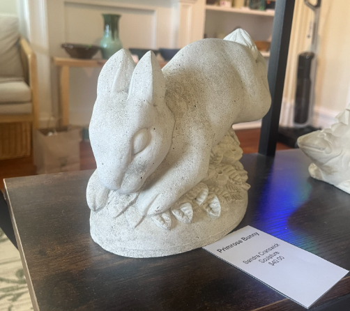 White rabbit sculpture on a dark table with a small label card beside it in a room setting