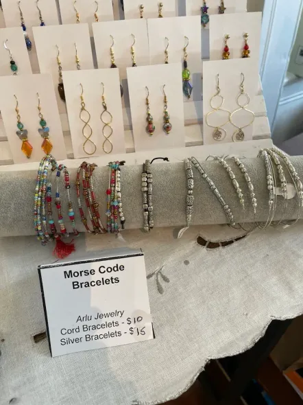 Bracelet display at a market table with colorful beaded and silver wire bracelets and a price sign