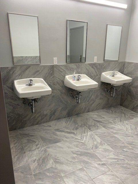 A bathroom with three sinks and three mirrors.