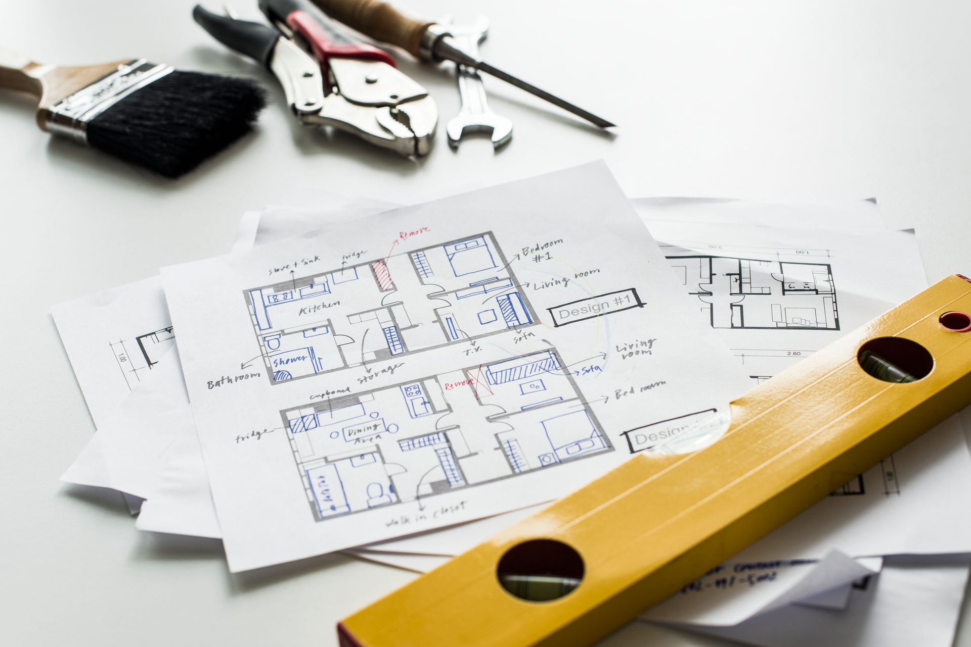 Architectural blueprints on a desk with measuring tools, tape measure, and yellow spirit level