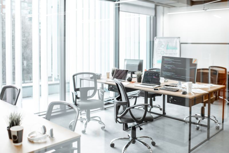 An office with a lot of desks and chairs and a lot of windows.
