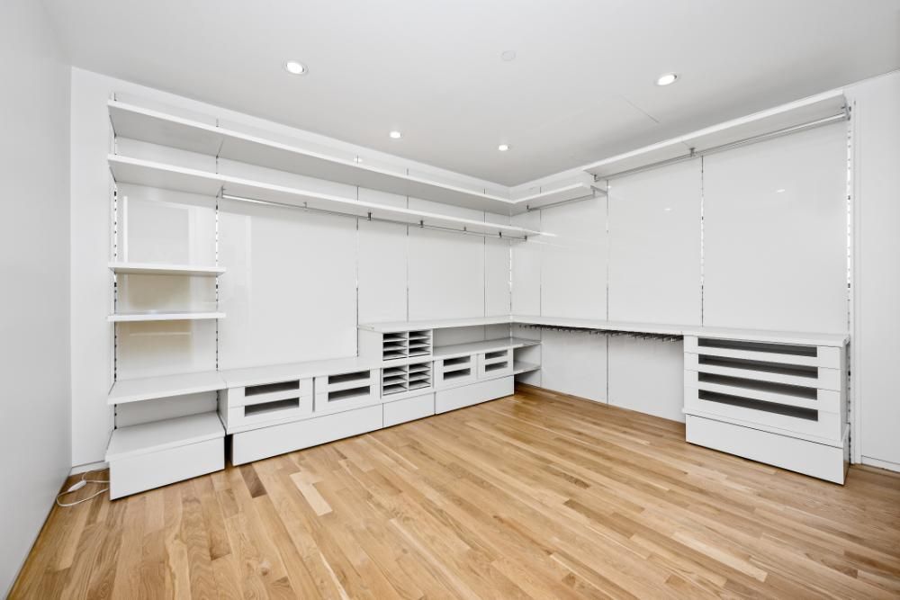 A large empty room with hardwood floors and white shelves.