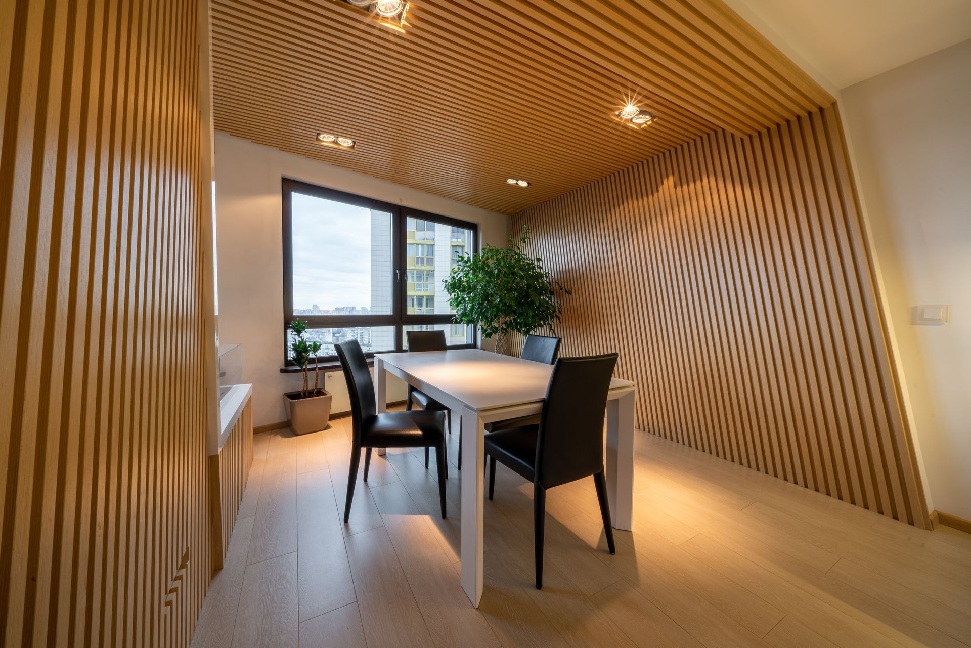 Modern dining room with wood-slat walls, long table, and chairs by a large window