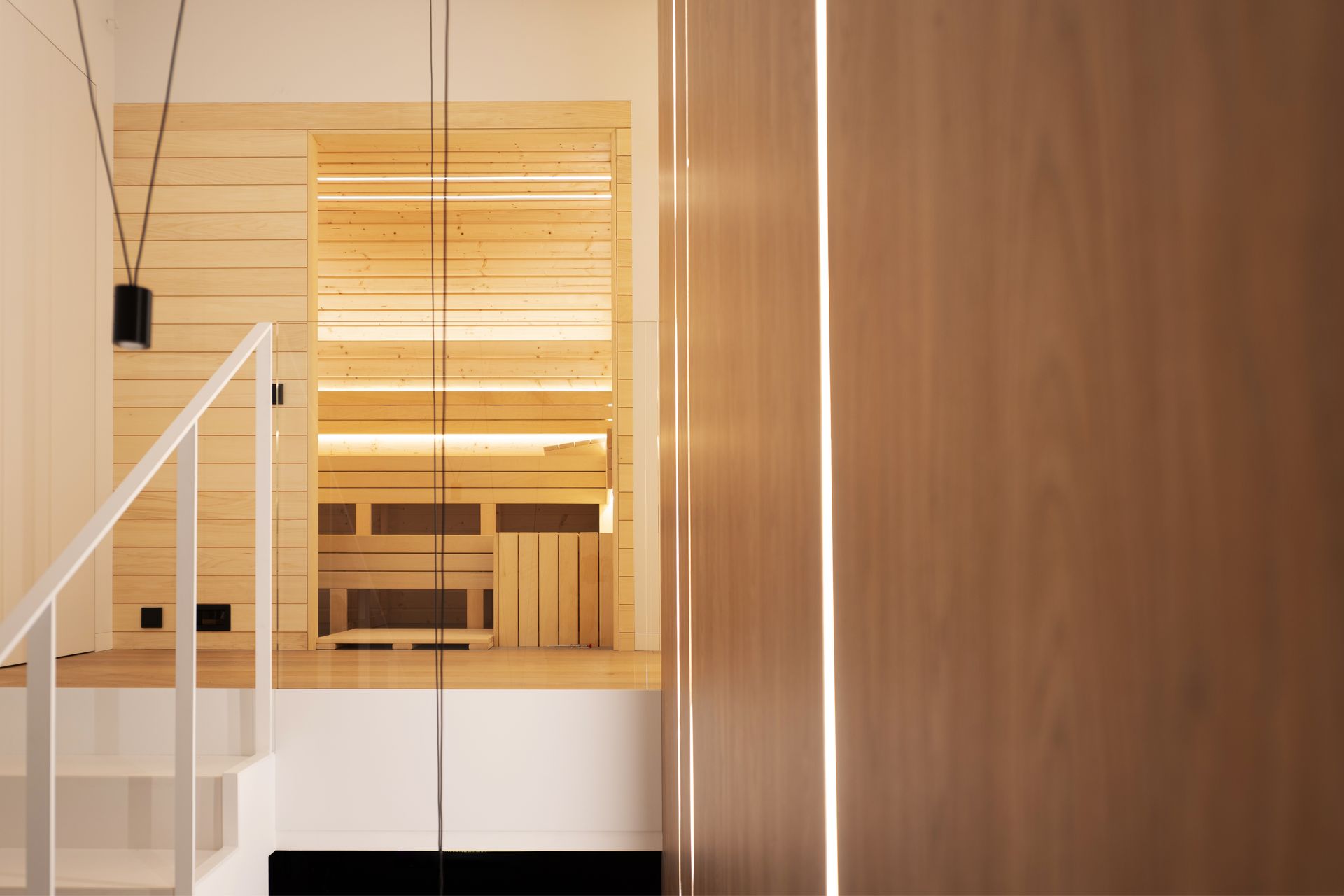 Modern wooden interior with stairs, white railing, and warm lighting