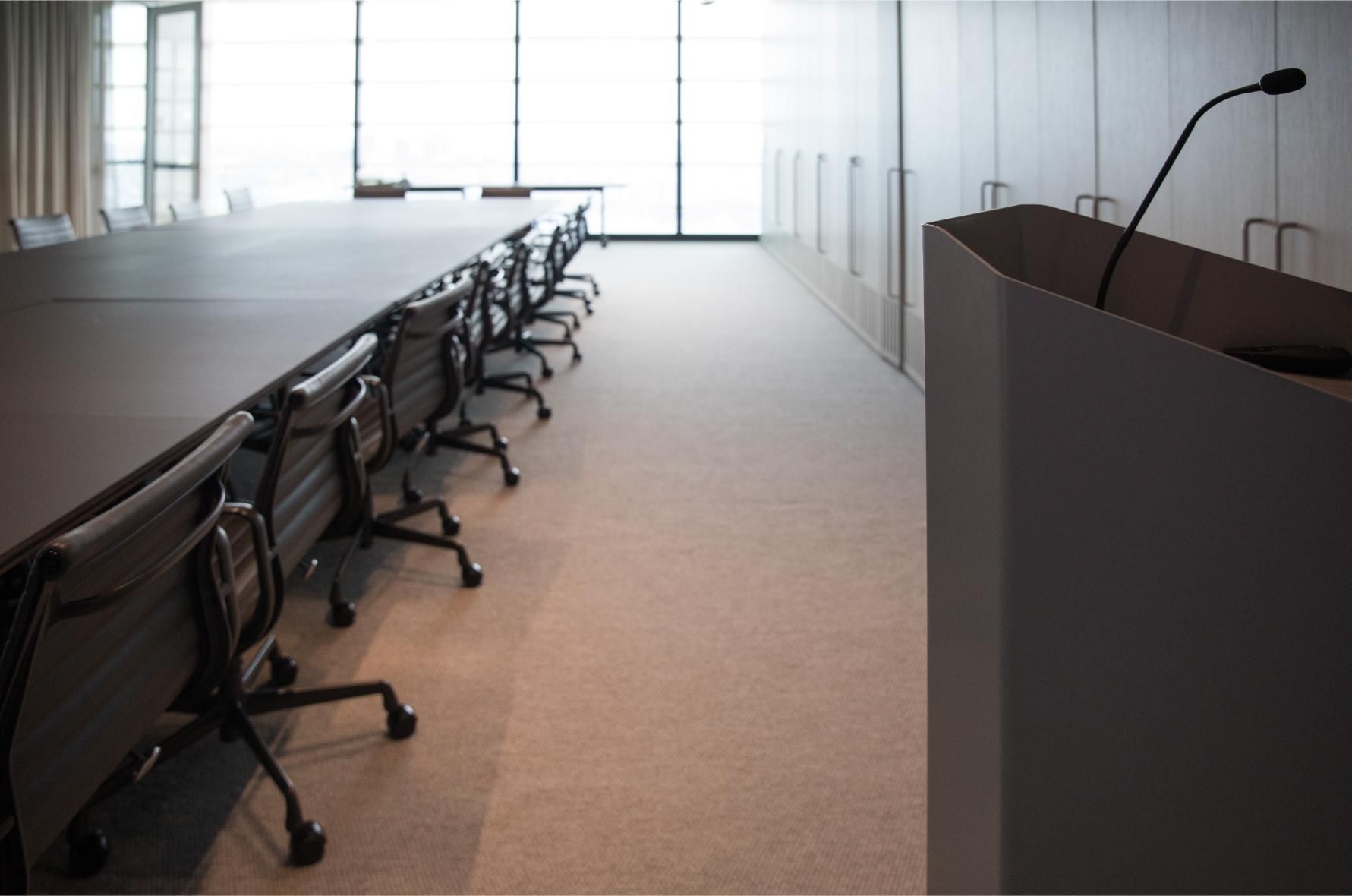 A conference room with a long table and chairs and a podium
