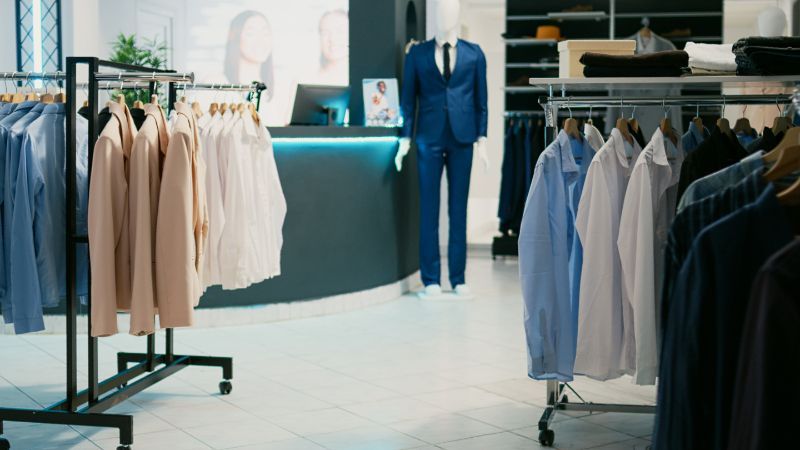 A store filled with lots of clothes and a mannequin wearing a suit.