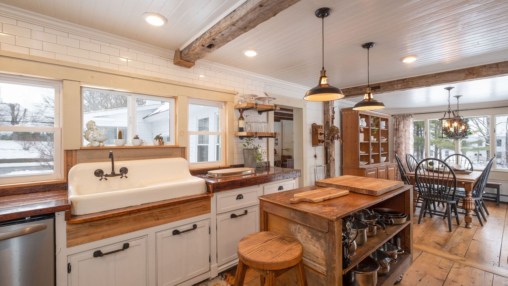 Rustic kitchen with a large sink, wooden island, and dining area with a circular table.