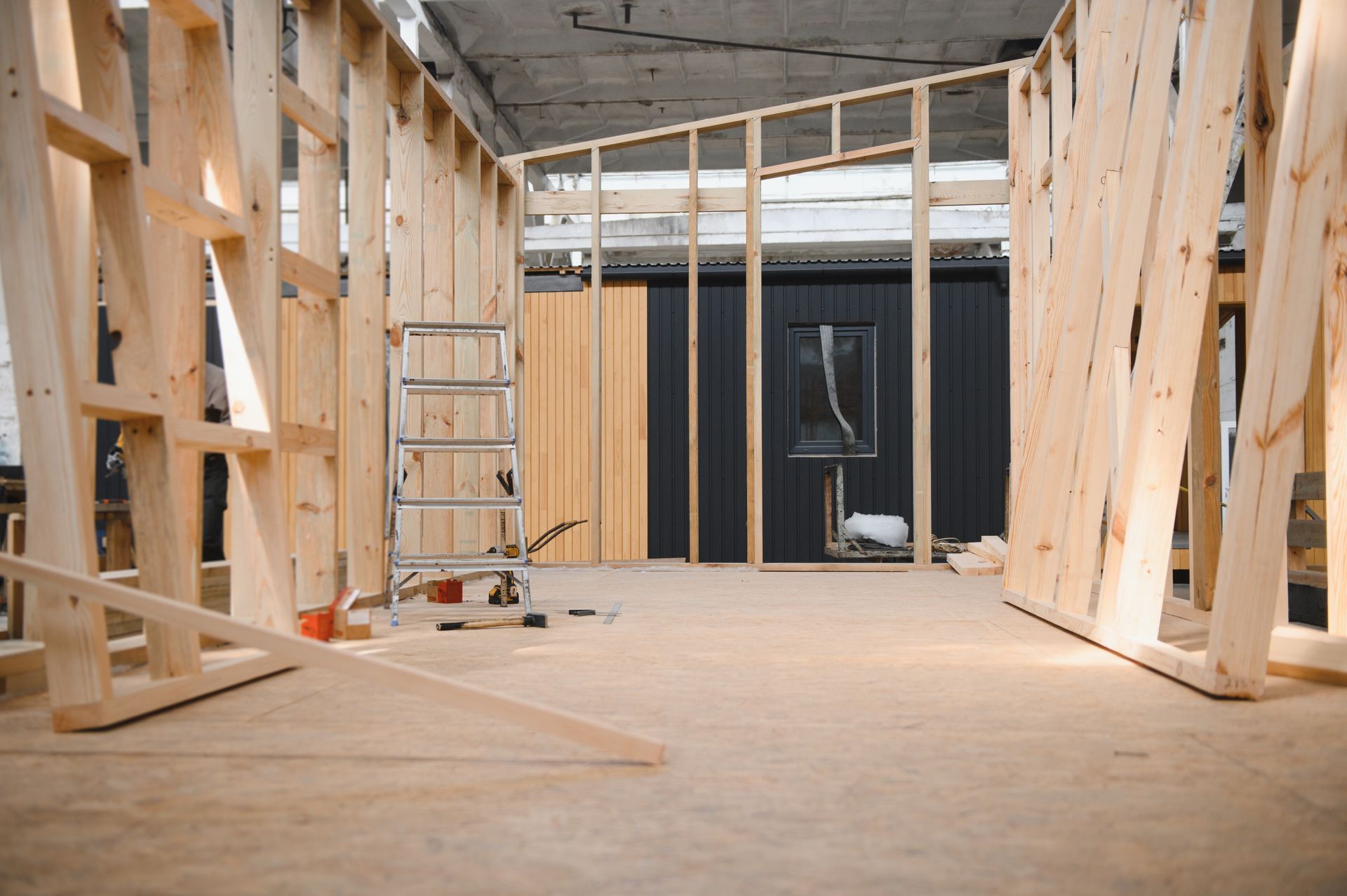 Interior framing construction with wooden studs. A small wall with a window is visible.