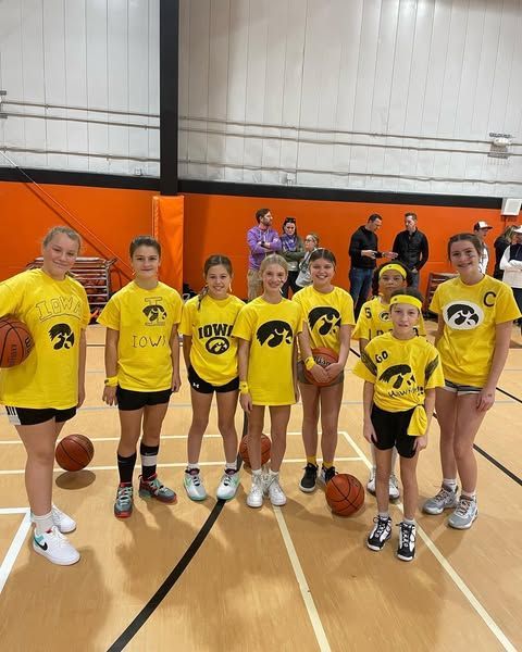 Youth basketball team in yellow jerseys posing indoors on a gym court with basketballs.