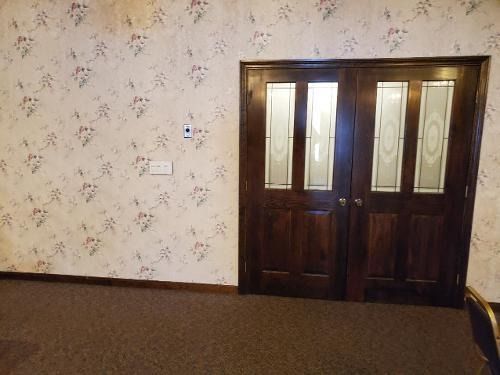 Empty room with floral wallpaper and dark wooden double doors with frosted glass panels