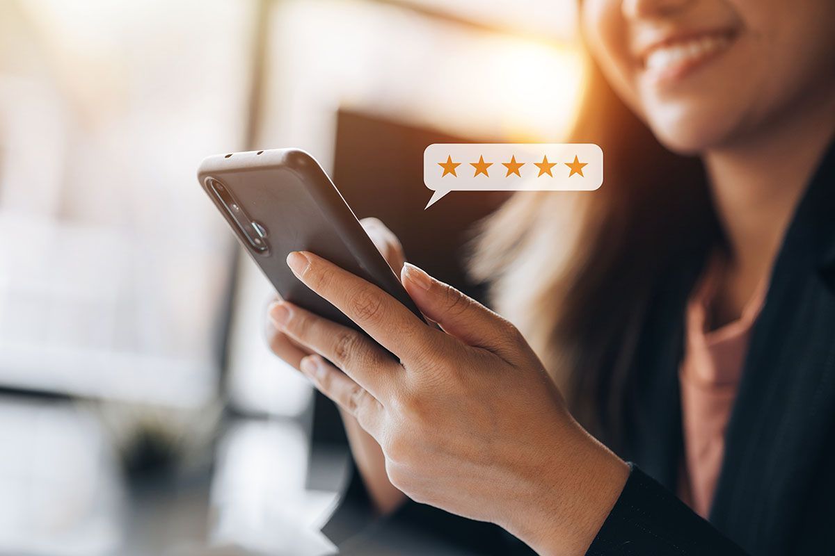 Person holding a smartphone with a five-star rating icon on screen