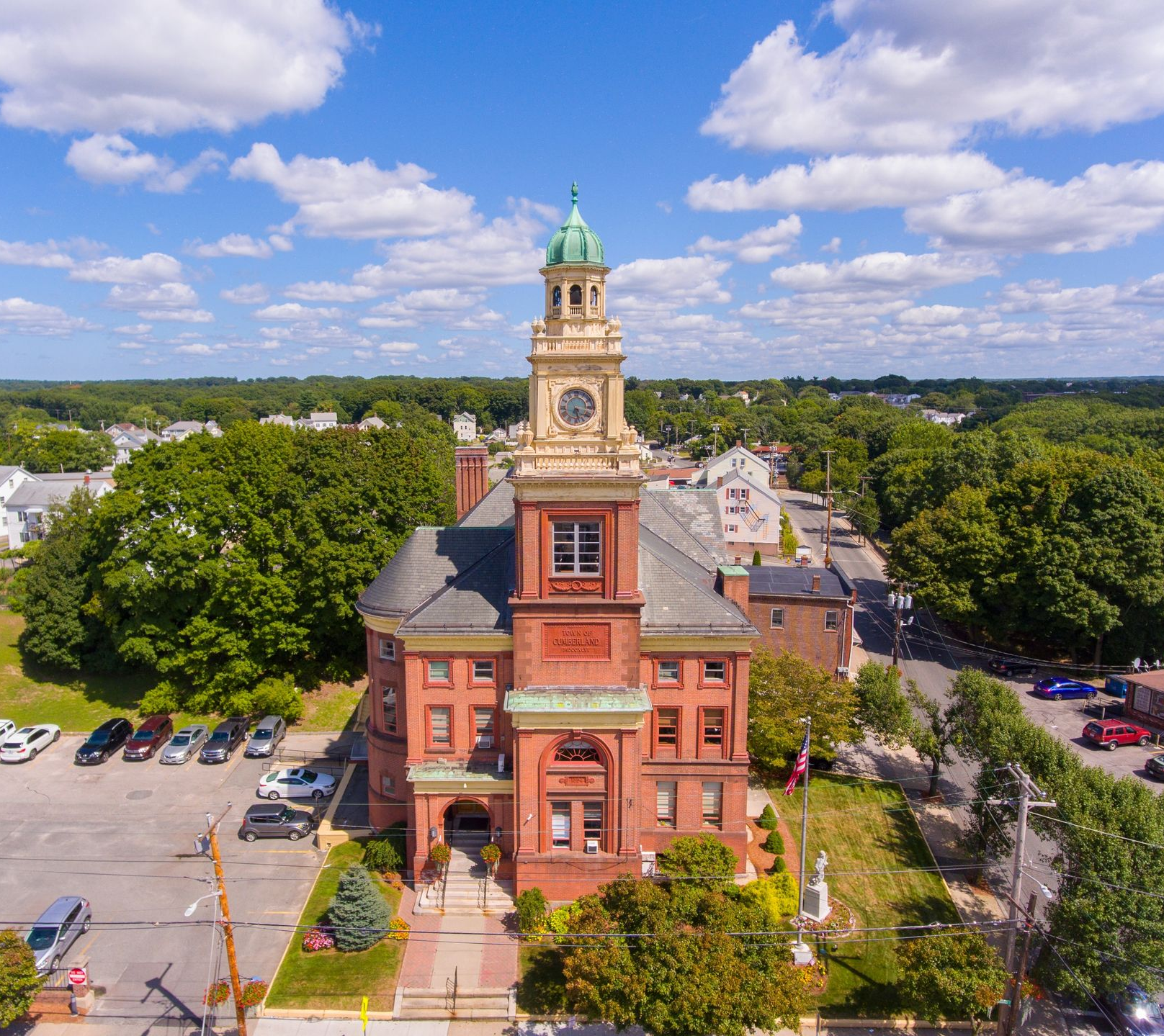 Historic red-brick clock tower on a civic building, viewed from above under a partly cloudy sky.