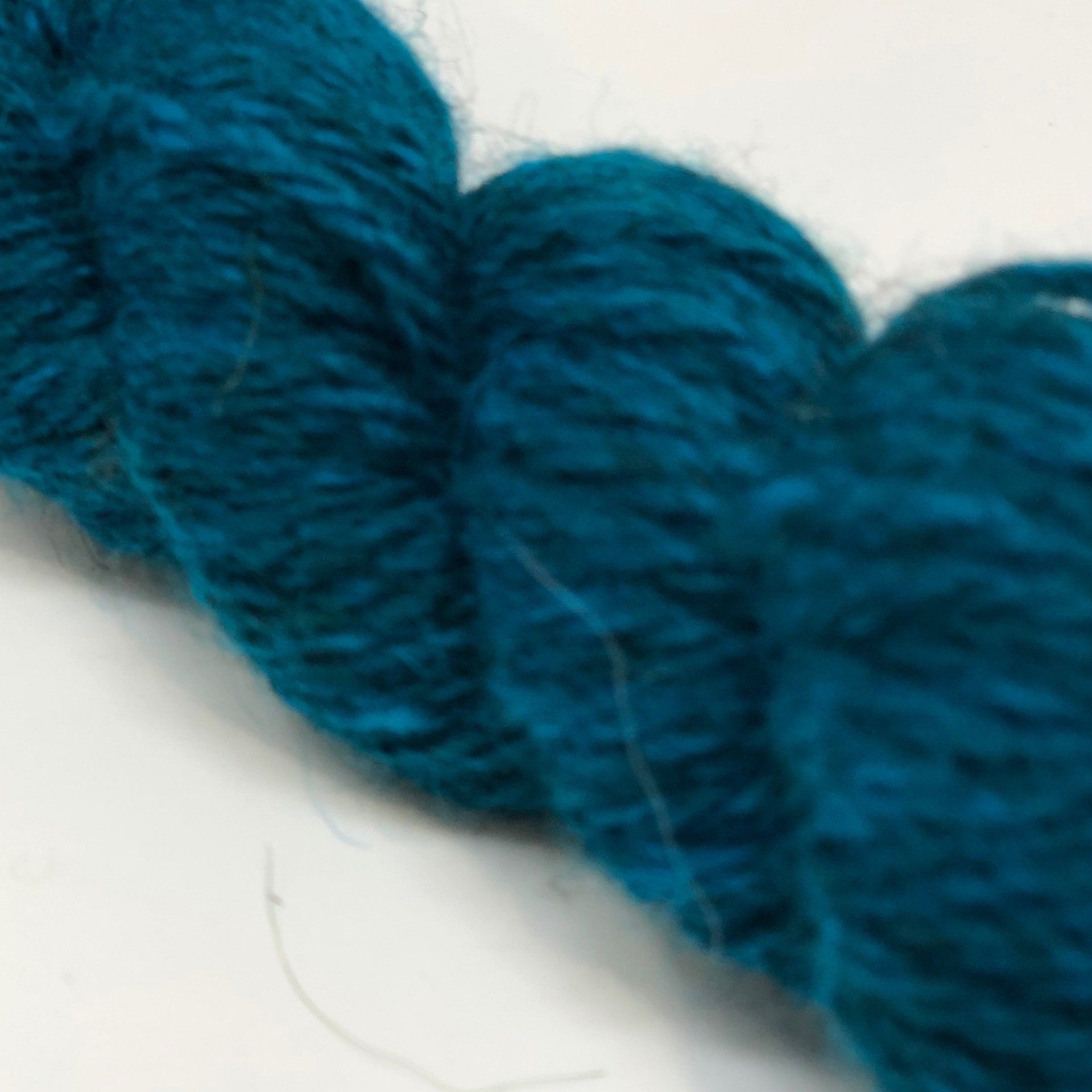 Close-up of a twisted skein of teal-colored yarn.
