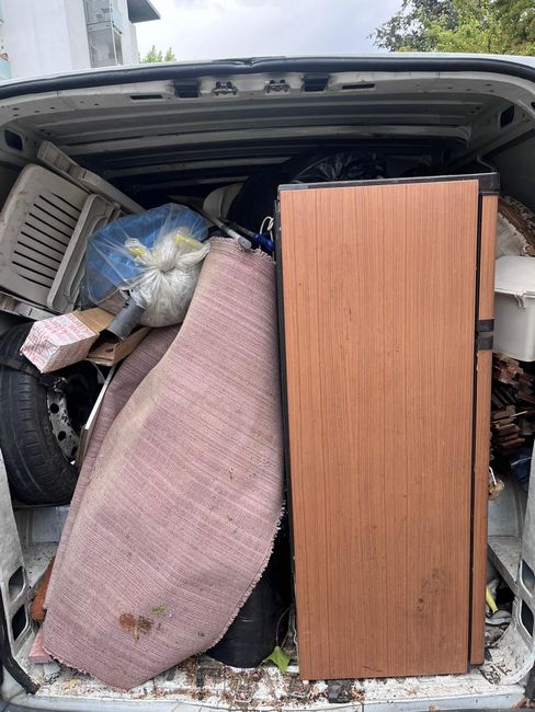 Contenitore di stoccaggio ingombro di legno di scarto, attrezzi e detriti, coperto da un tetto di lamiera ondulata.