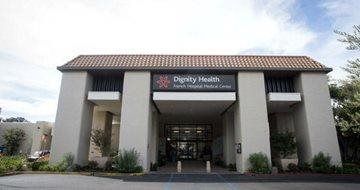 Front view of a beige clinic building with columns and a “Dignity Health” sign above the entrance