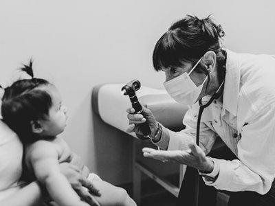 Doctor examining a child with an otoscope in a clinic