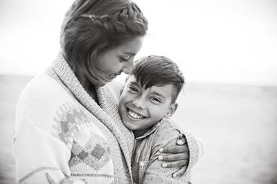 Woman hugging smiling child outdoors in black-and-white photo